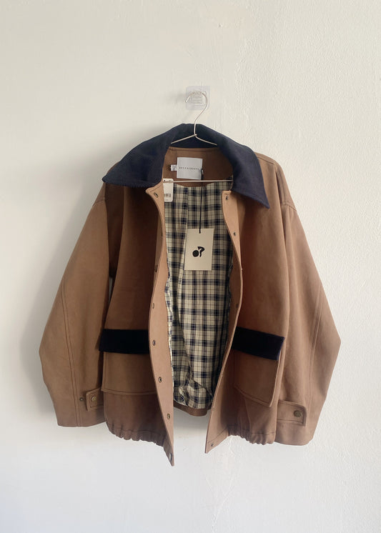Brown jacket with plaid lining on a hanger against a white background