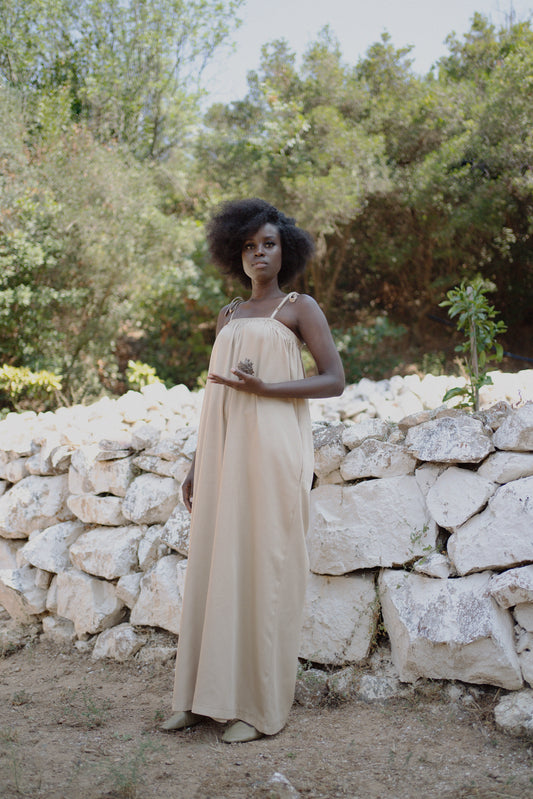Woman standing wearing a beige jumpsuit