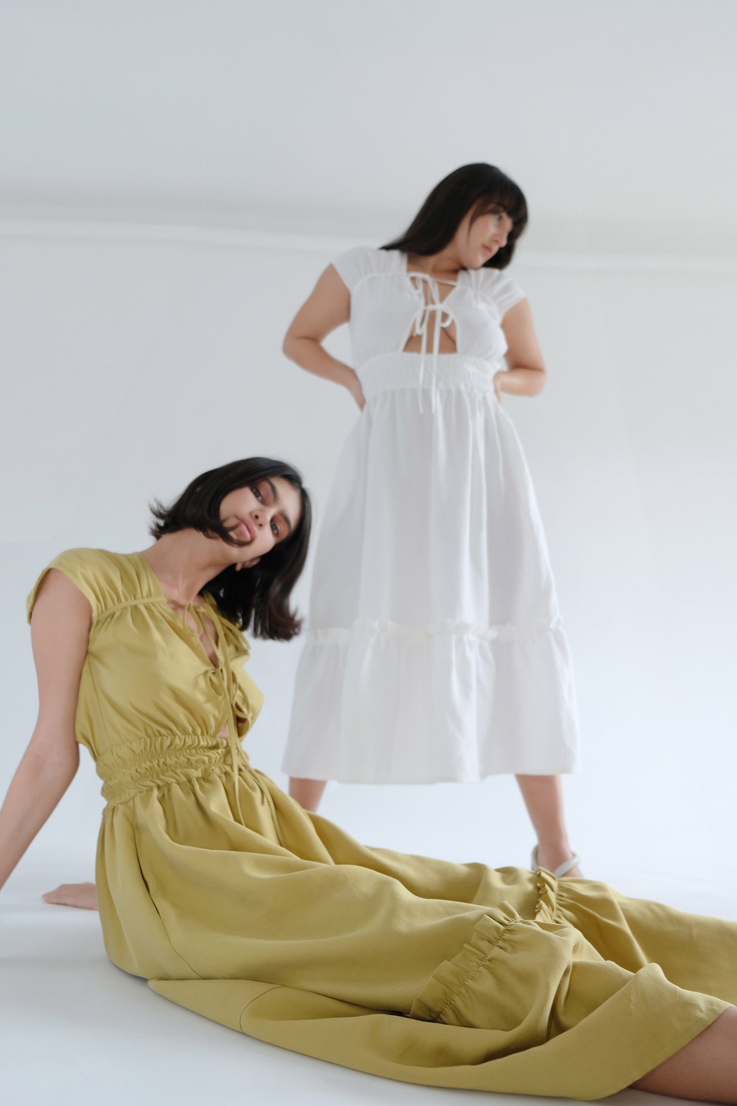 Two girls wearing olive and white midi dresses
