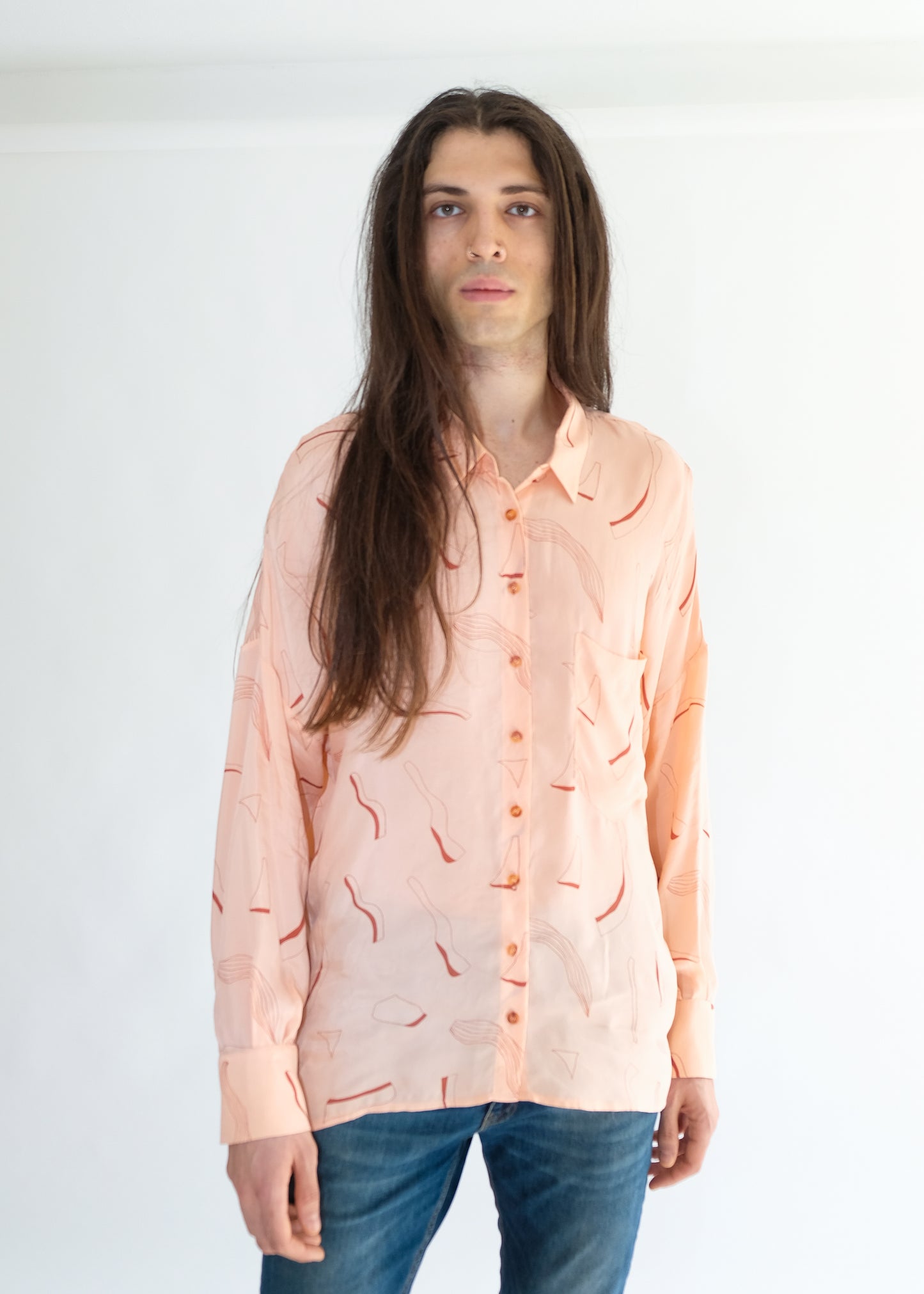Guy wearing pink silk printed shirt and blue jeans