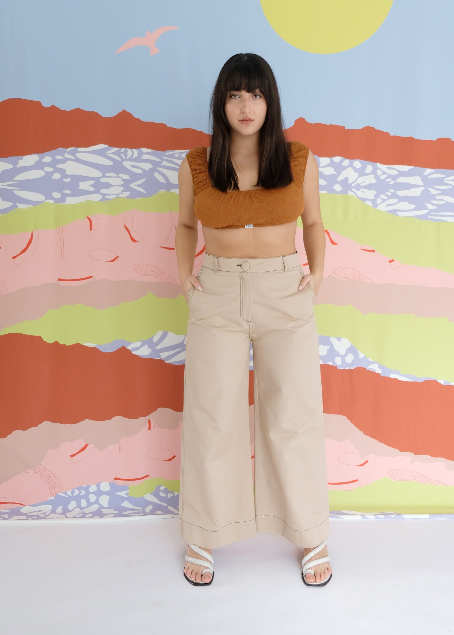 Girl standing wearing brown top and brown trousers