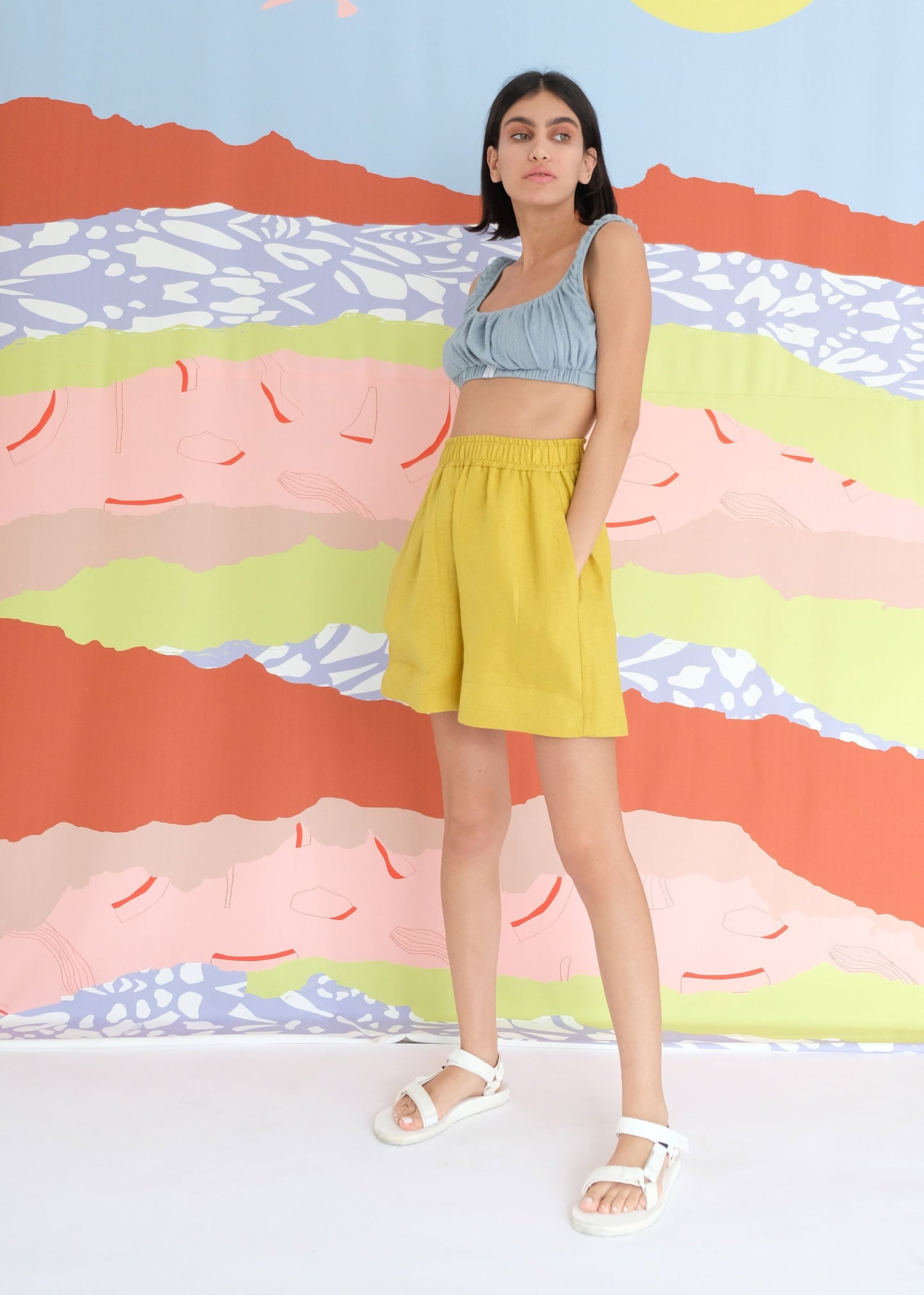 Girl standing wearing blue top and yellow shorts