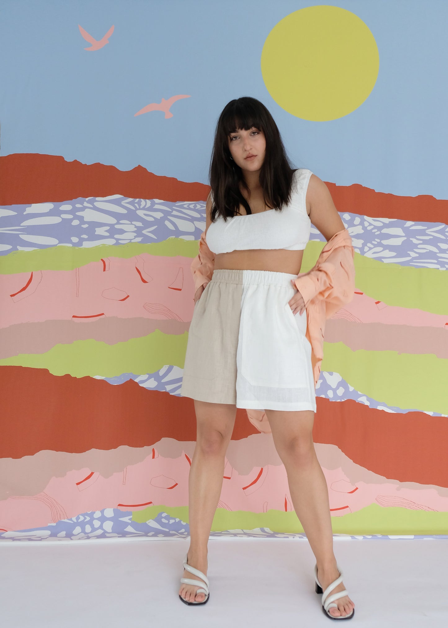 Girl standing wearing white top with brown and white shorts