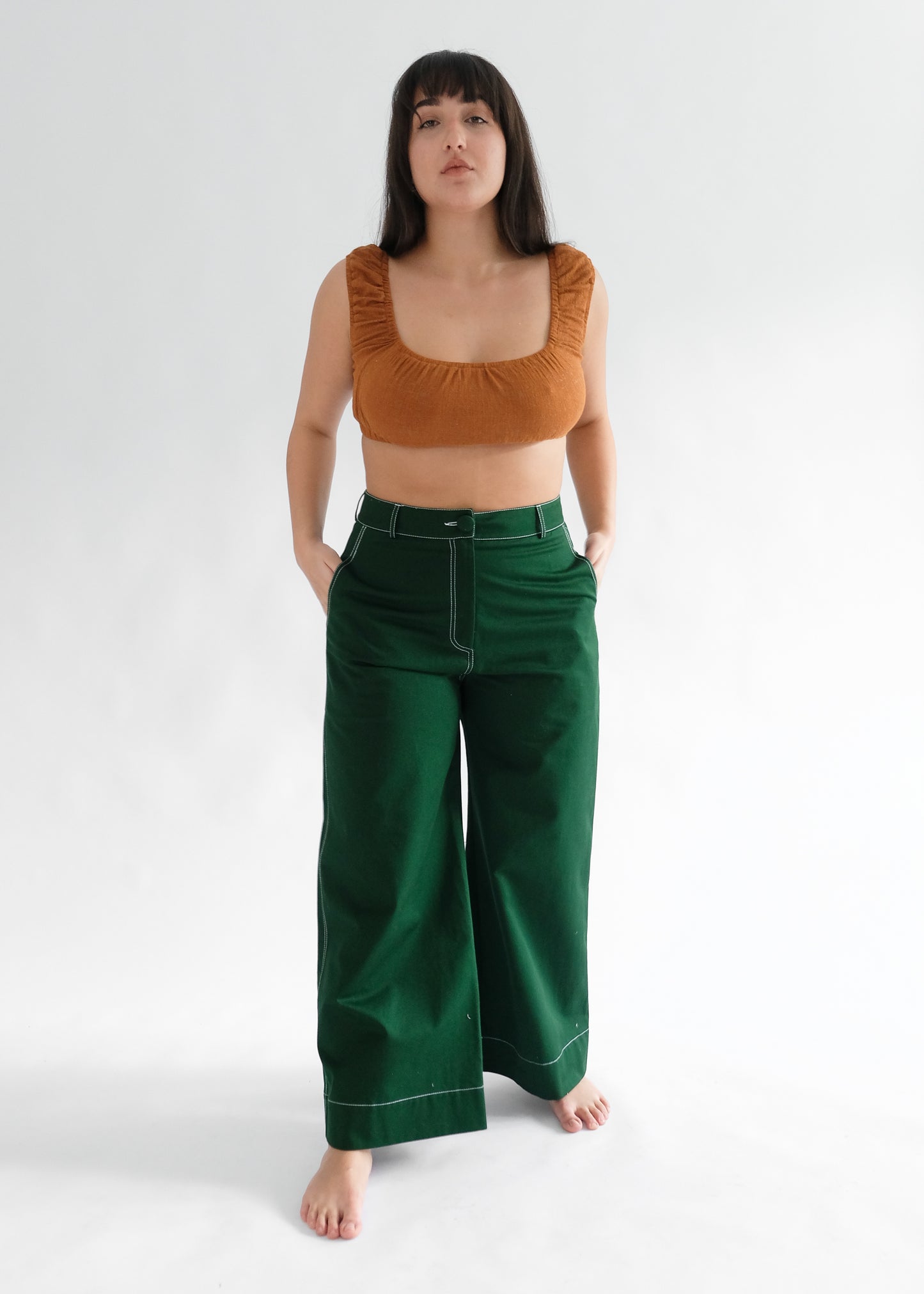 Woman wearing brown crop top and pine green trousers