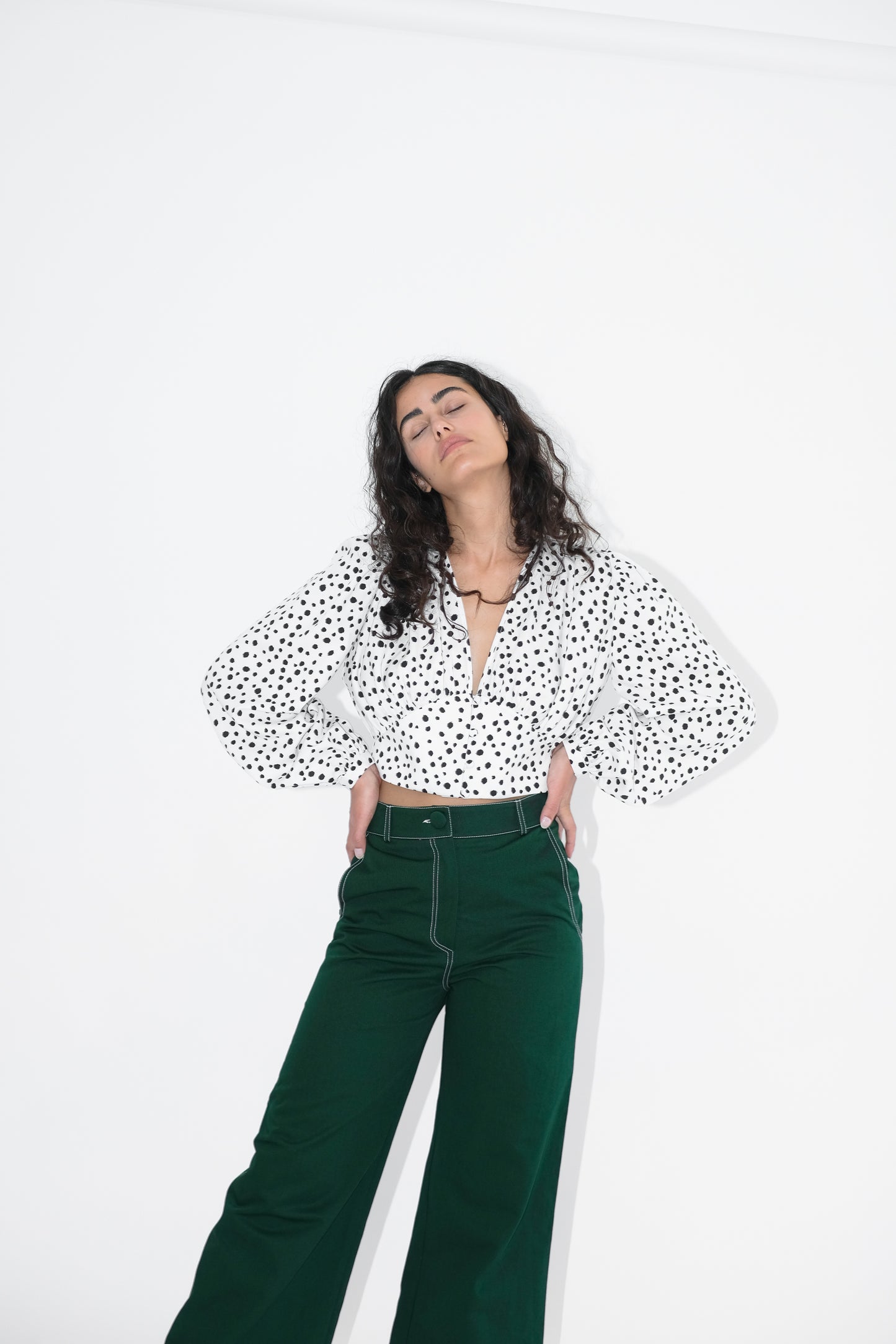 Woman wearing polka dotted white shirt and green trousers