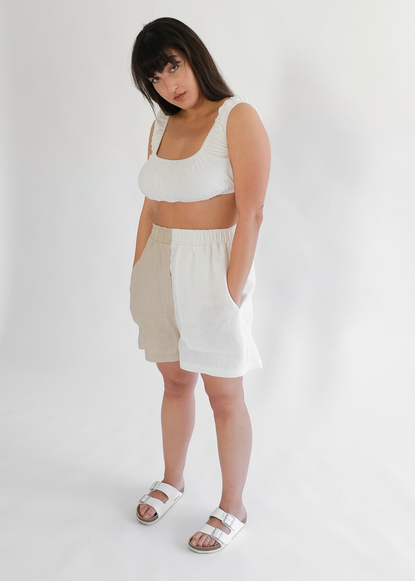 Girl standing wearing white top with brown and white shorts