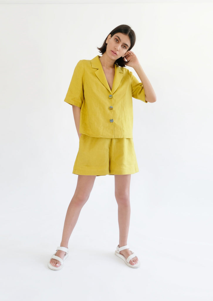 Girl standing wearing yellow shirt and shorts 