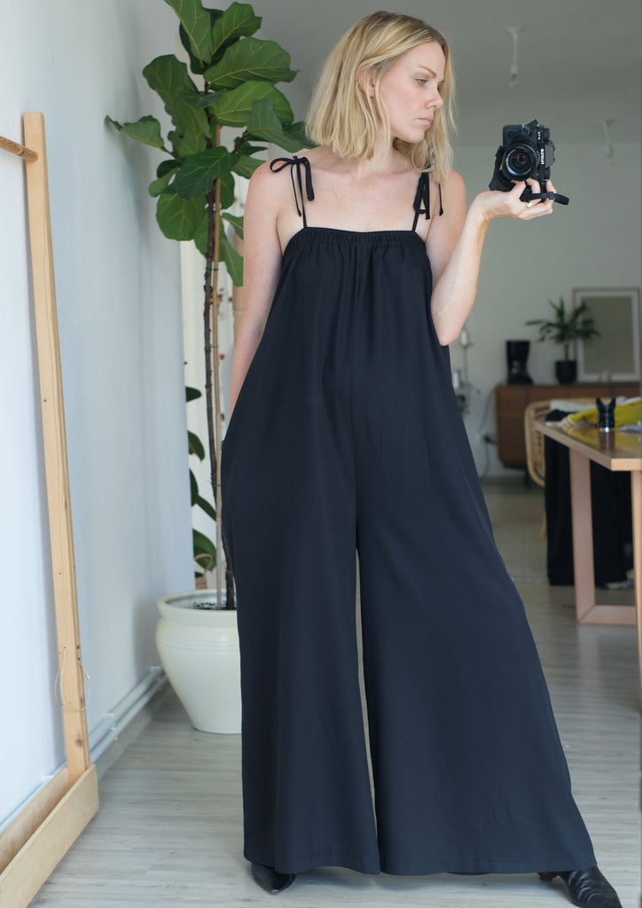 Standing woman wearing black jumpsuit taking a picture