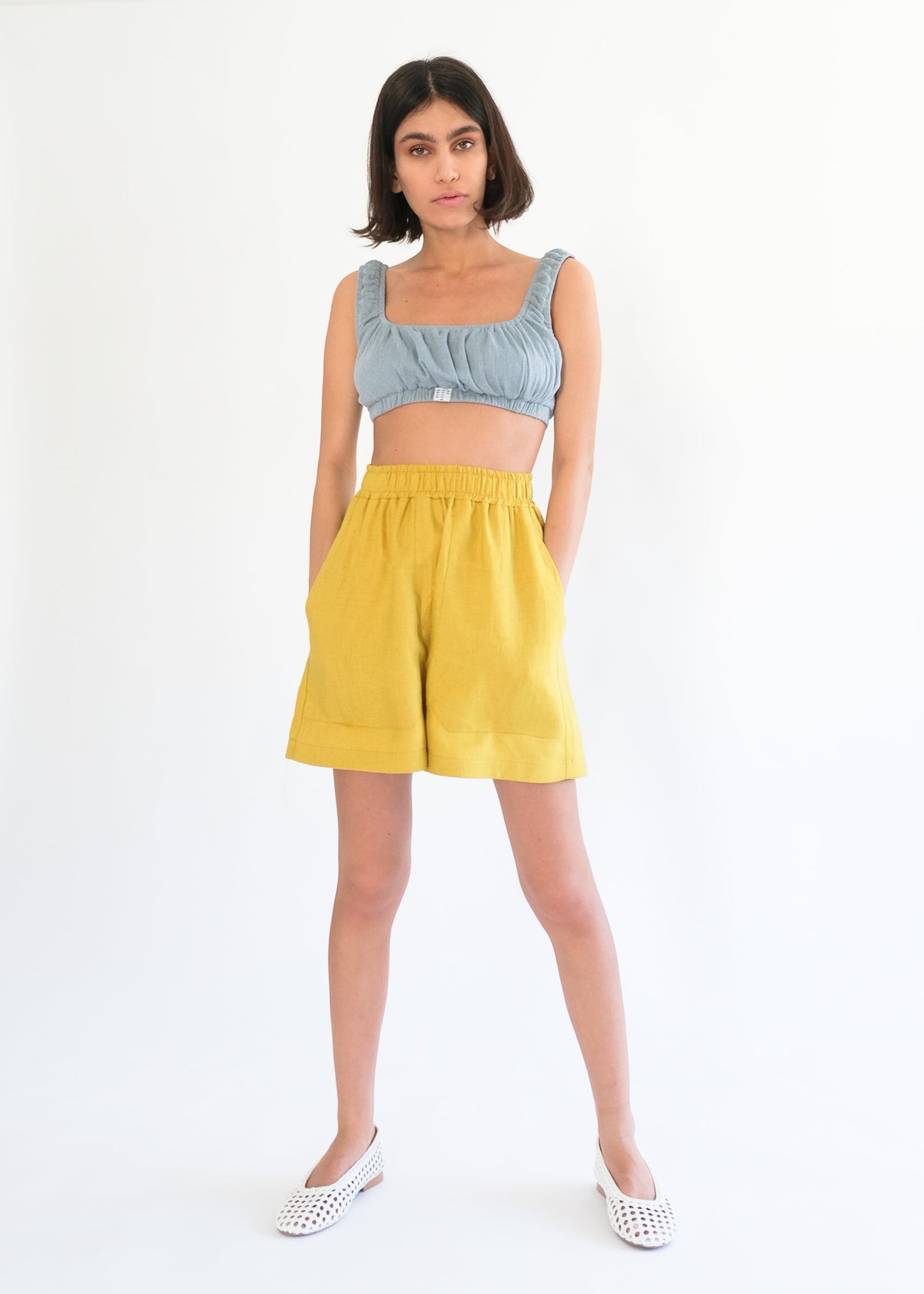 Girl standing wearing blue top and yellow shorts 