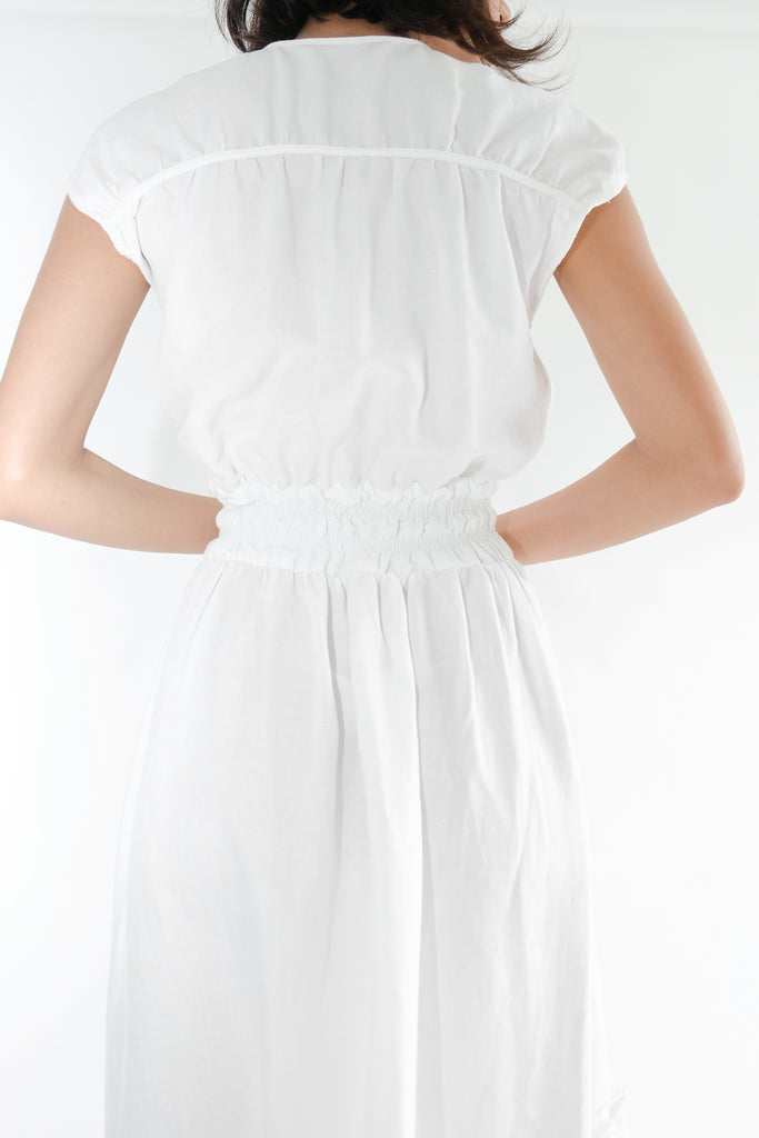 Girl standing backwards wearing white midi dress