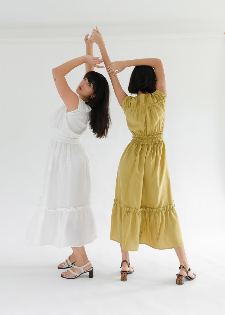 Two girls standing backwards wearing olive and white midi dresses 
