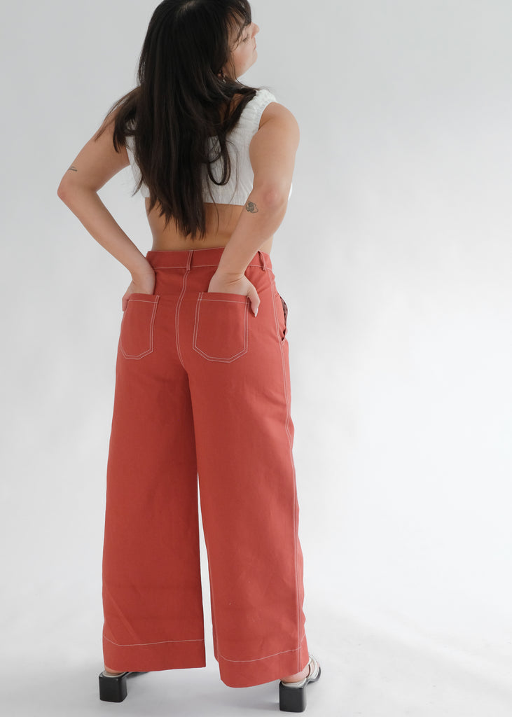 Back view of woman wearing red flared trousers and white tank top