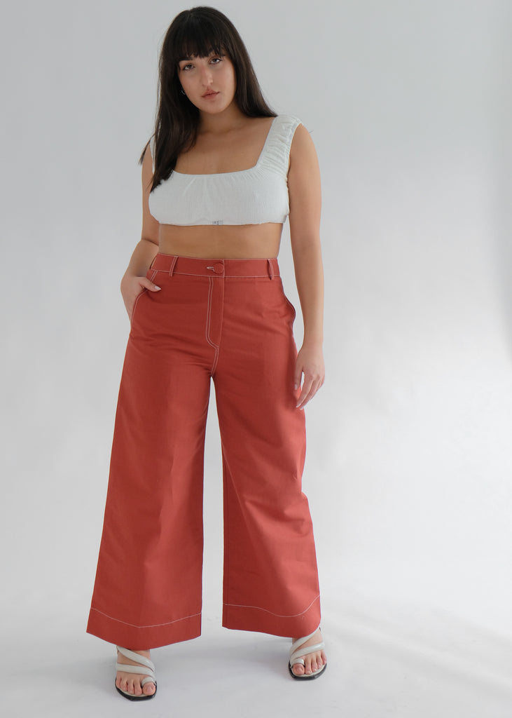Woman wearing white crop top and red flared trousers
