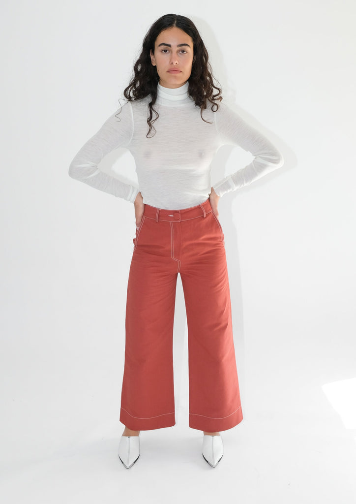Woman wearing white turtleneck with red flared trousers