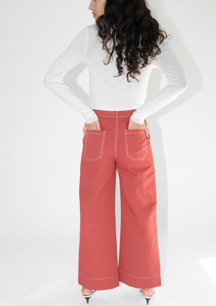 Back view of woman wearing red flared trousers and white turtleneck