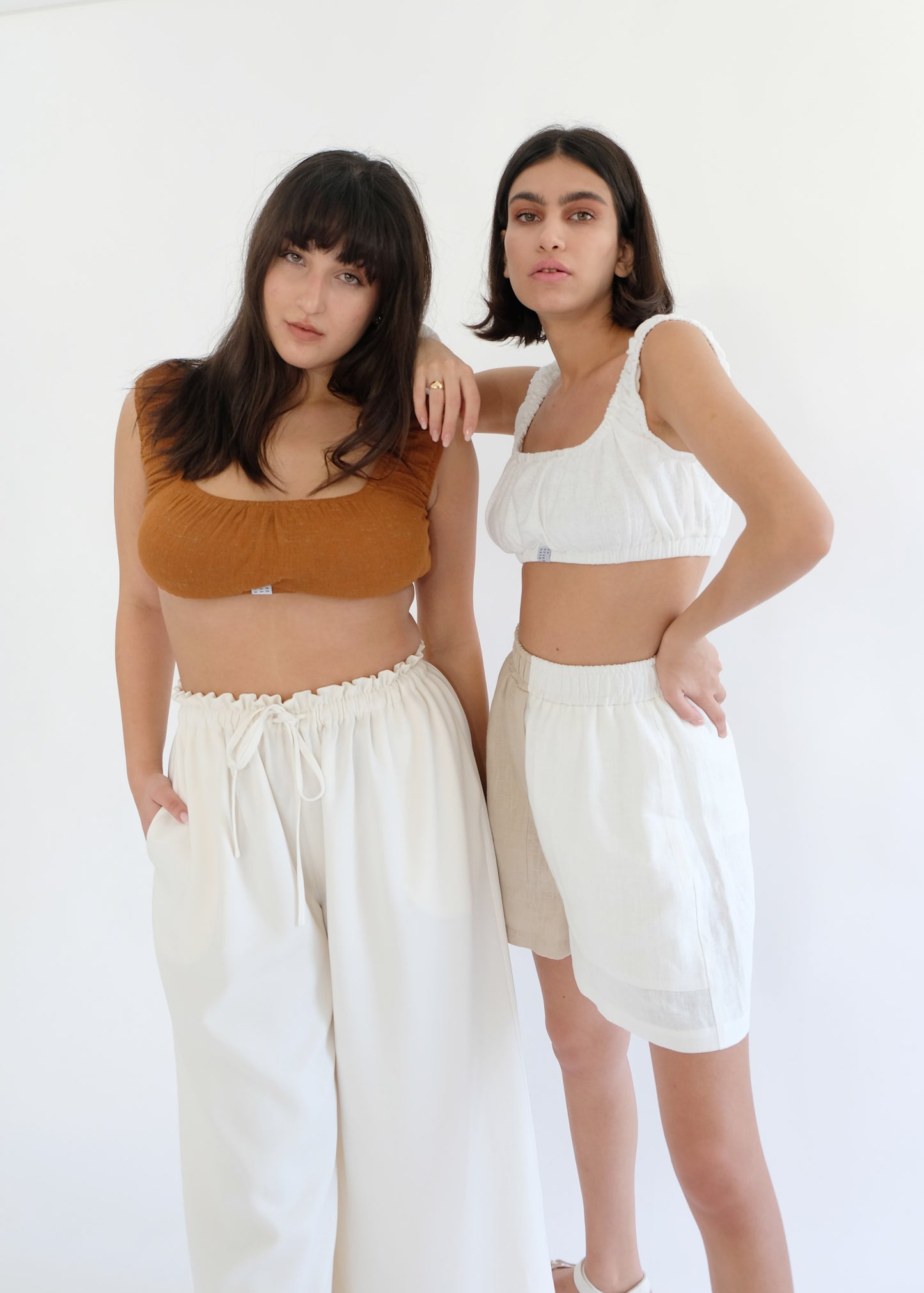 Two girls wearing brown tops with white trousers and shorts 